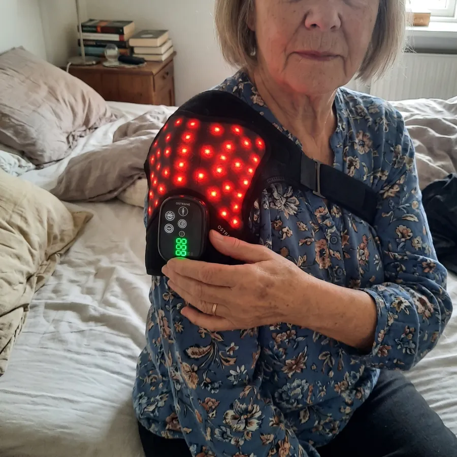 Susan, 62, sitting on her bed with the Ostrane Ember switched on over her shoulder